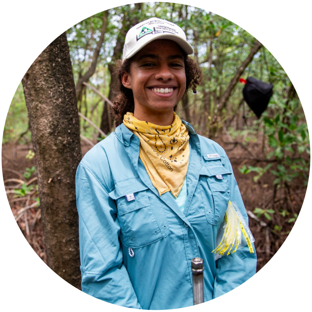 Scientist Jaxine standing in front of a coastal wetland being restored. She's part of a team helping states harness blue carbon to fight climate change.